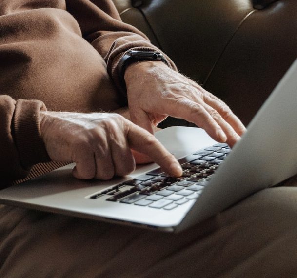 an elderly man uses a laptop computer